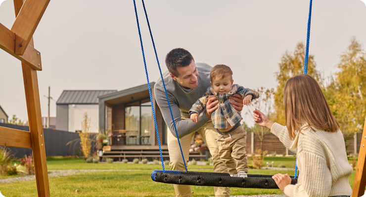 Счастливая семья на качелях у дома